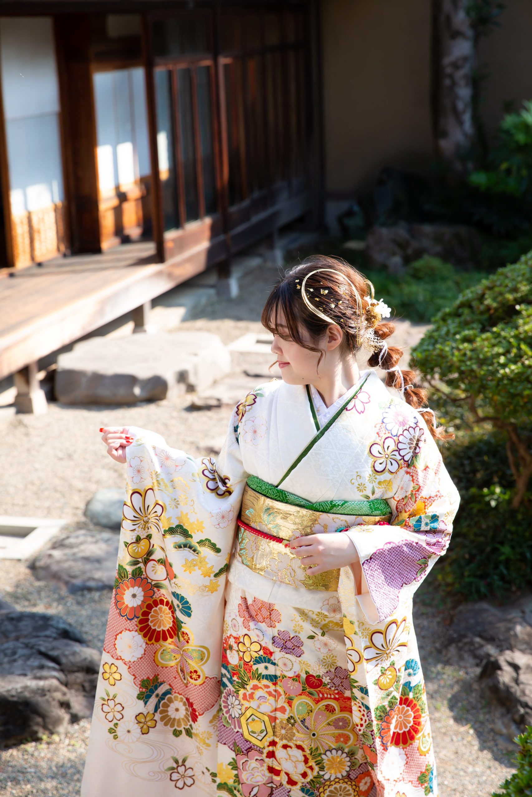 振袖を着て日本庭園に立つ女性