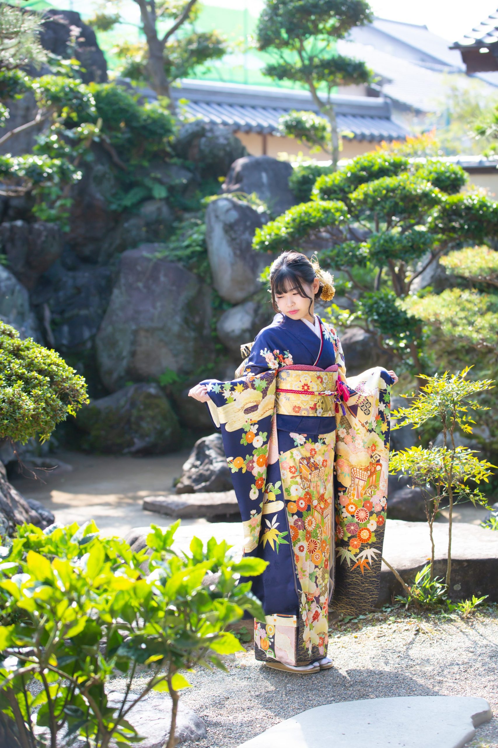 日本庭園に立つ振袖姿の女性