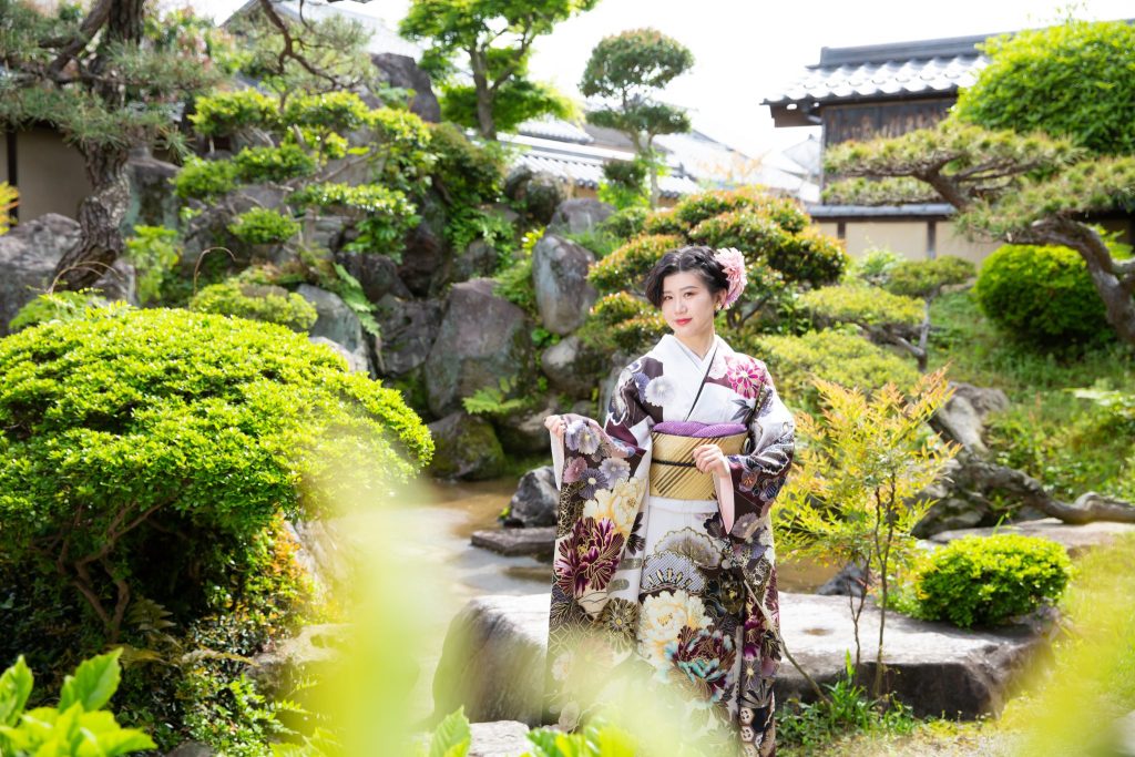 日本庭園に立つ振袖姿の女性