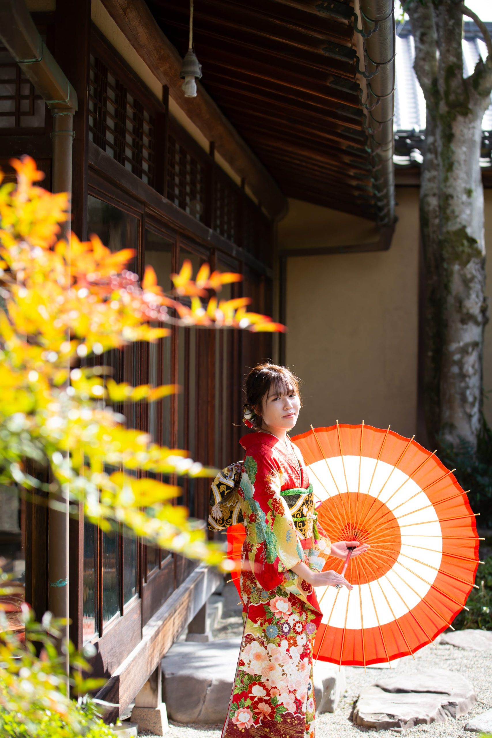 和傘を持って立つ赤い振袖姿の女性